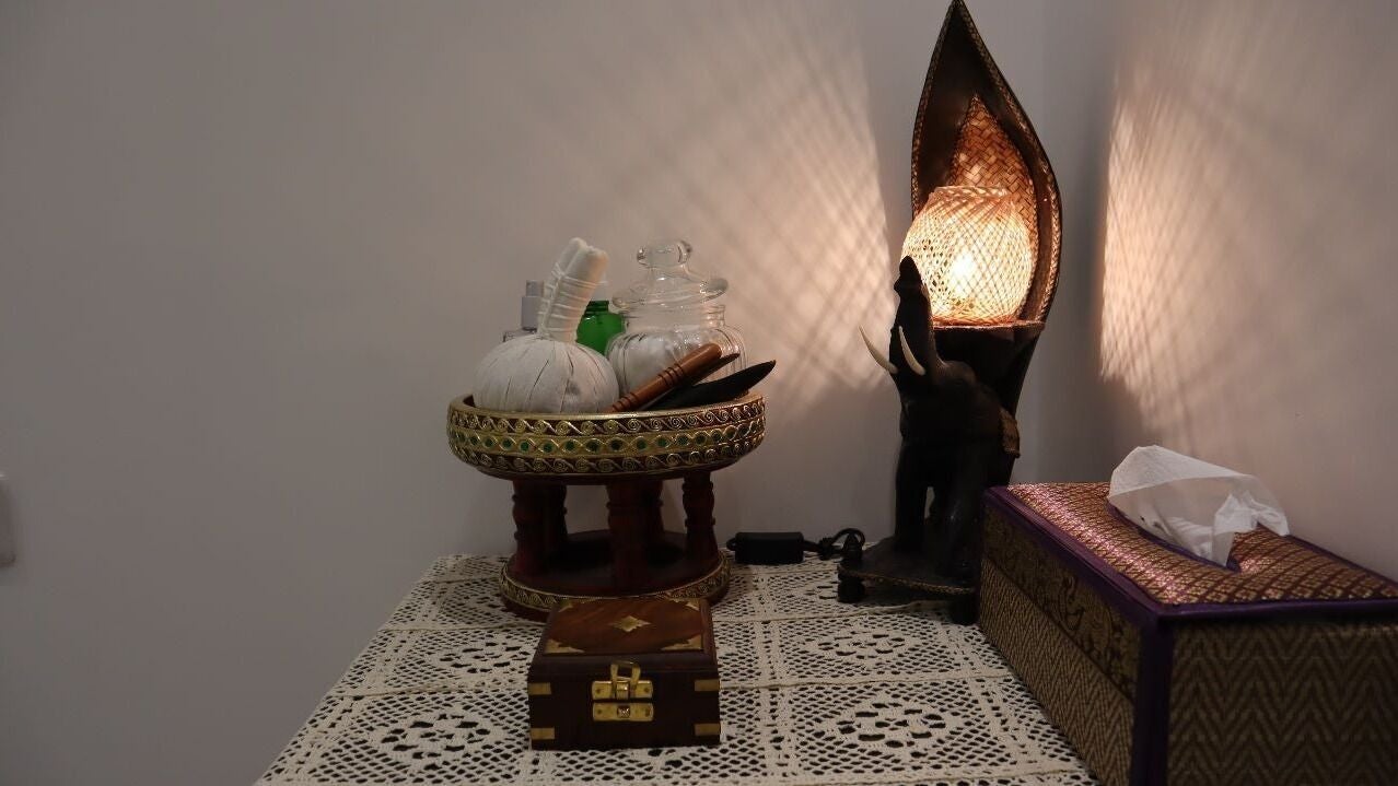 A treatment corner dressed with Thai wood carving and a warm table lamp